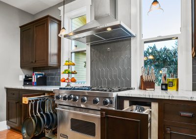 A newly remodeled kitchen with dark wood cabinets, grey marble countertops and classical Craftsman molding throughout..